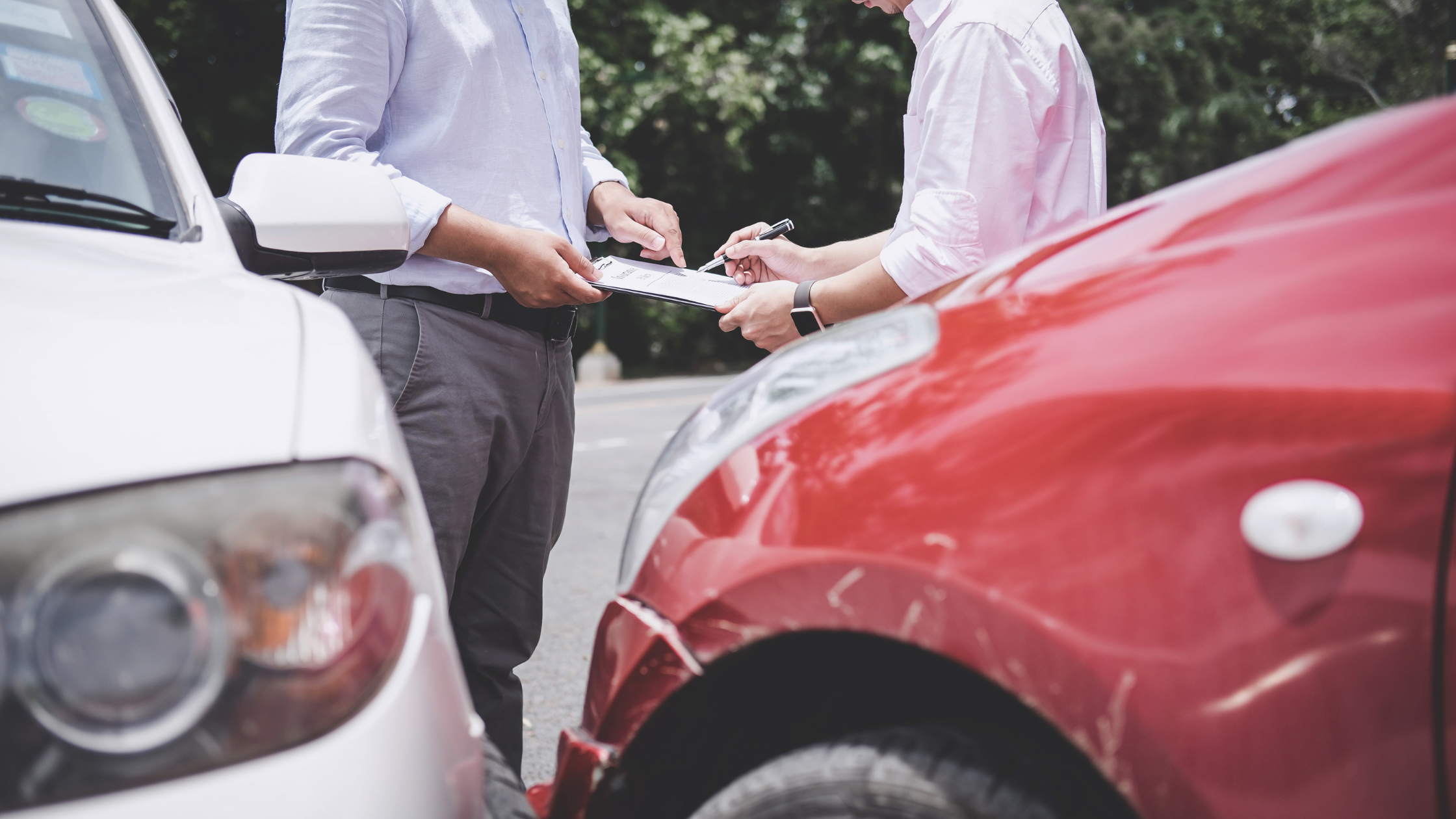 Two individuals exchanging information after a car accident, dealing with insurance companies.